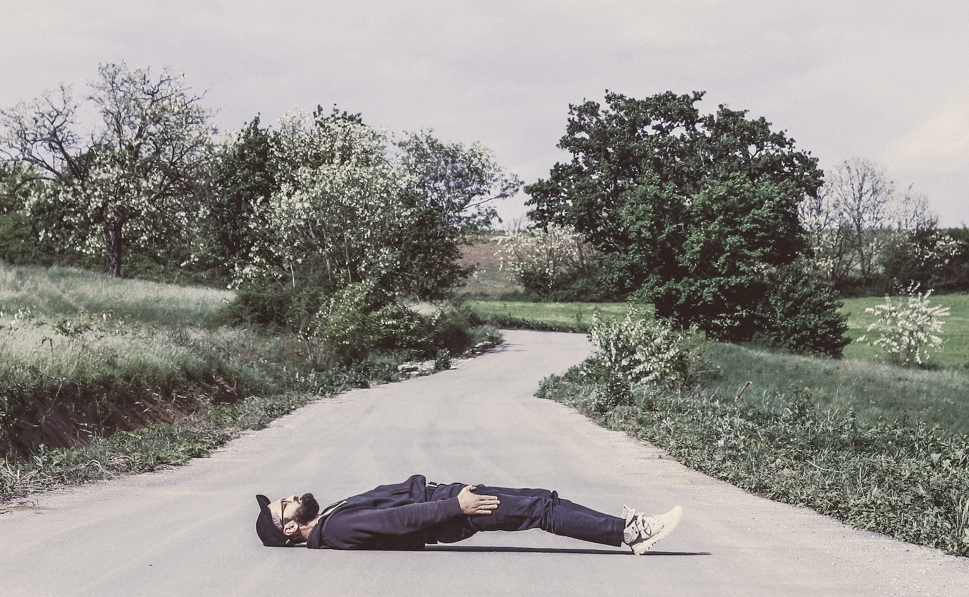 Person lying across a narrow country road