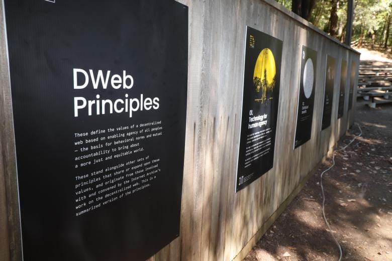 A fence at DWeb Camp with posters along it showing the DWeb Principles